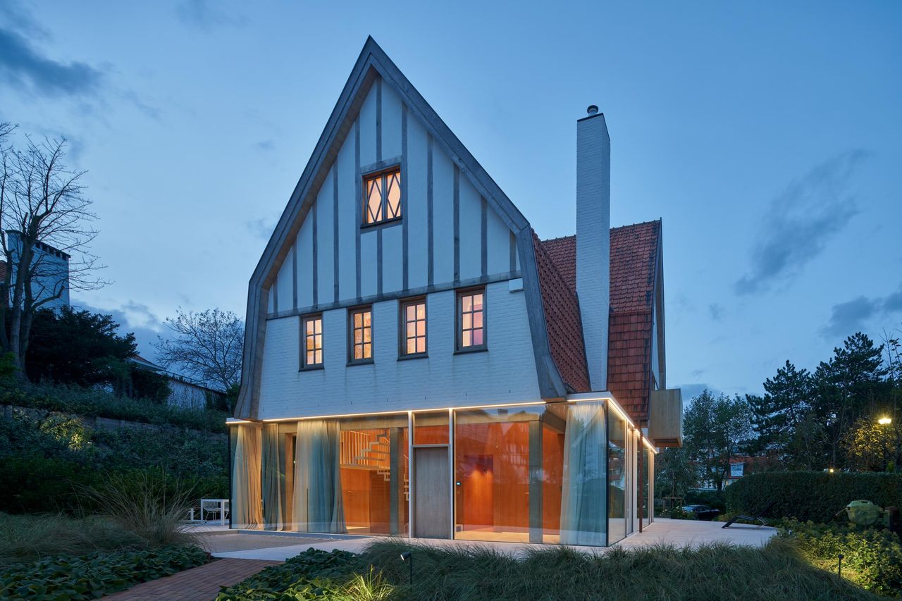 Three-quarter view at dusk of a gabled house with a fully glazed Sky-Frame ground floor