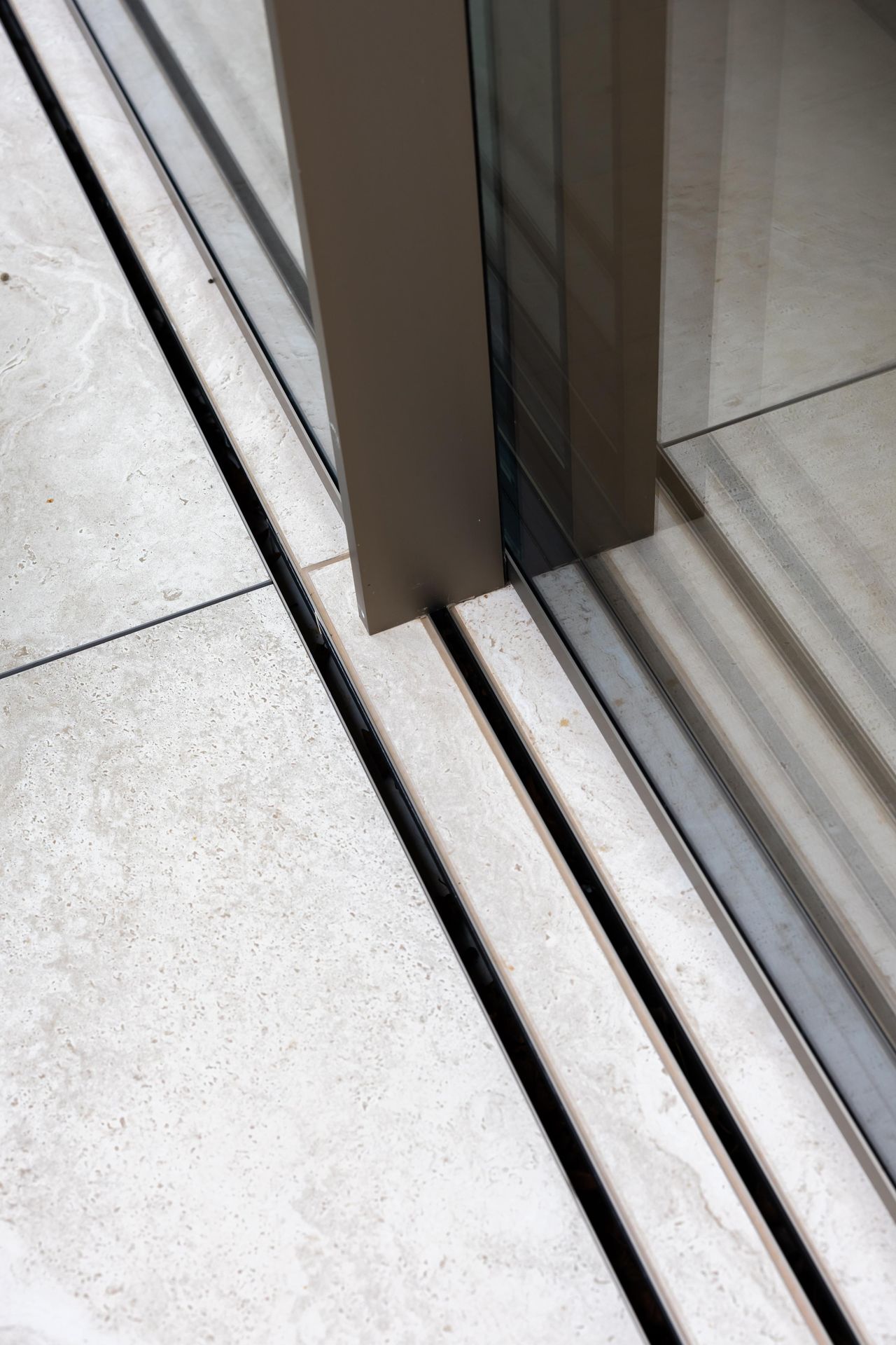 Close-up of the Sky-Frame Plain threshold, the track set into a narrow gap in continuous stone flooring