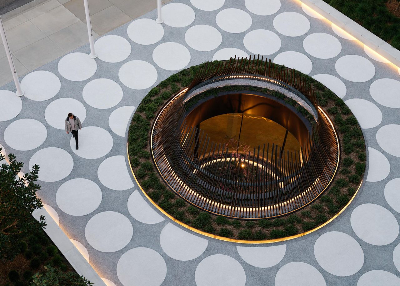 Aerial view of a circular glazed Sky-Frame Arc pavilion ringed by planting in a paved plaza